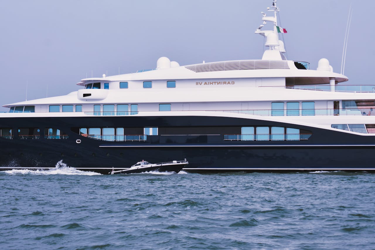 Luxury contemporary private yacht and small motorboat floating in blue ocean against cloudless sky